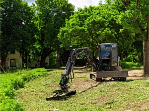 Excavator with brush mower being used to mow a slope