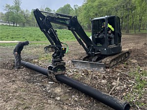 Culvert pipe being installed to make a trail crossing through a swale